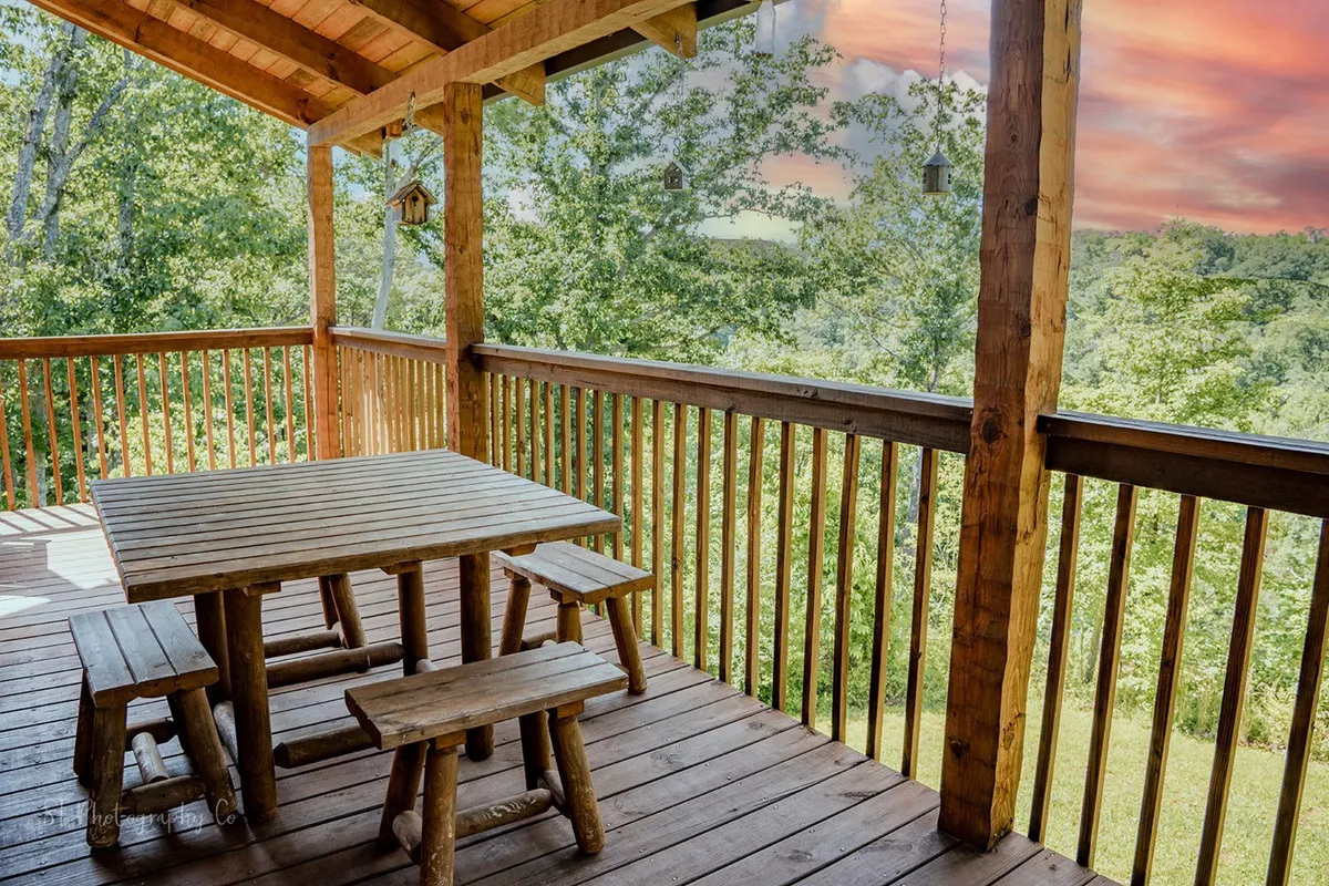An outdoor dining setup featuring a wooden table and benches surrounded by lush greenery and hanging bird feeders. The space is ideal for shared meals, wildlife watching, and enjoying the natural surroundings at any time of day.