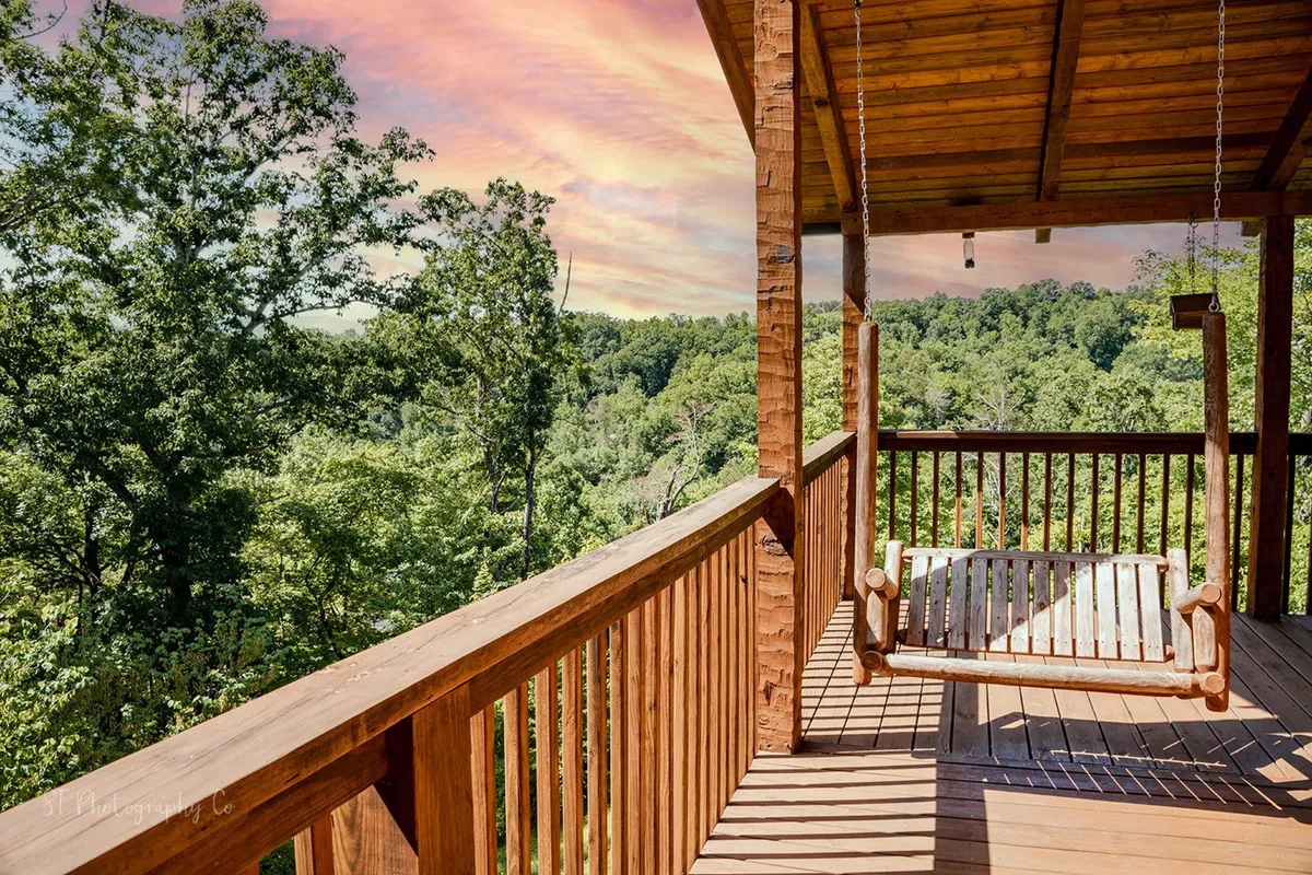 A serene outdoor scene with a wooden swing overlooking a lush green landscape under a pastel sunset sky. The swing is positioned for quiet enjoyment of nature, suggesting a peaceful retreat for both pets and owners.